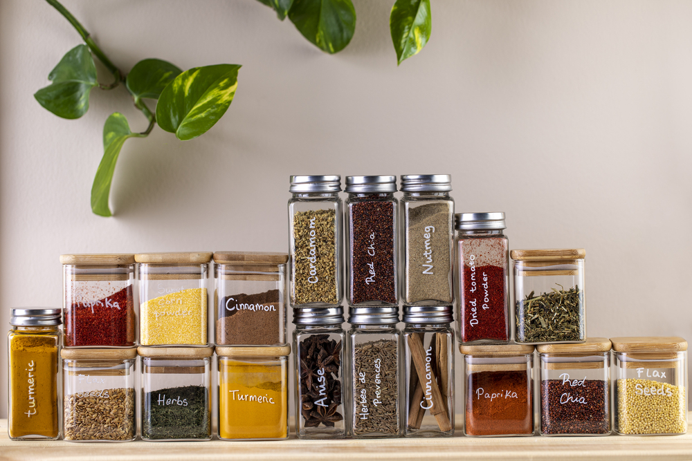 Vista de un estante de especias en la cocina, donde frascos de vidrio etiquetados permiten una fácil identificación y acceso a diversas especias, mostrando una organización estética y funcional.