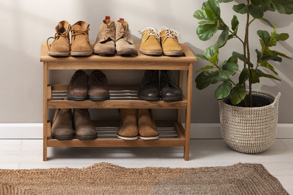 Zapatero de madera elegante con zapatos organizados, acompañado de una planta decorativa, ideal para mantener el recibidor ordenado y estilizado.