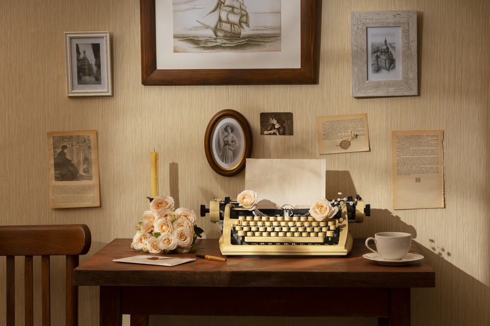 Un encantador escritorio vintage presenta una máquina de escribir antigua rodeada de flores y decoraciones de época, reflejando un estilo retro que revive historias del pasado y añade un toque cálido y acogedor a cualquier espacio.