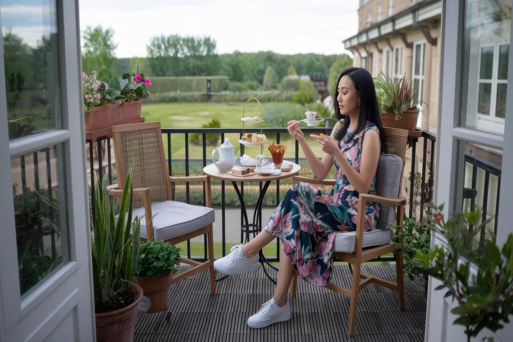 Una pequeña terraza acogedora, con una mujer sentada disfrutando de un té, rodeada de plantas y elegante mobiliario, perfecta para maximizar el espacio exterior.