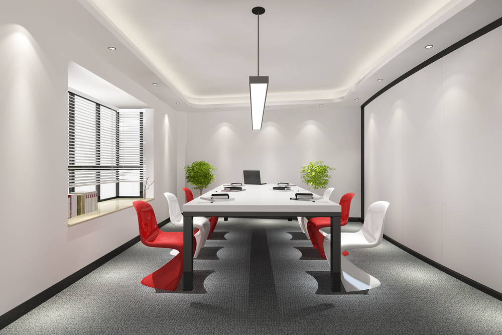 Moderna sala de reuniones con una mesa larga y sillas rojas y blancas, diseñada para fomentar un ambiente de trabajo cómodo y productivo.