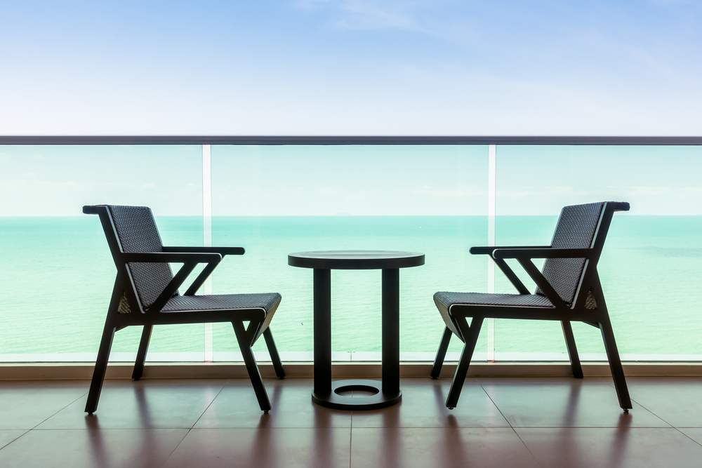 Un balcón presenta un par de sillas modernas y una mesa redonda, perfectas para disfrutar de la vista al mar. El ambiente cálido y relajante invita a momentos de confort al aire libre.