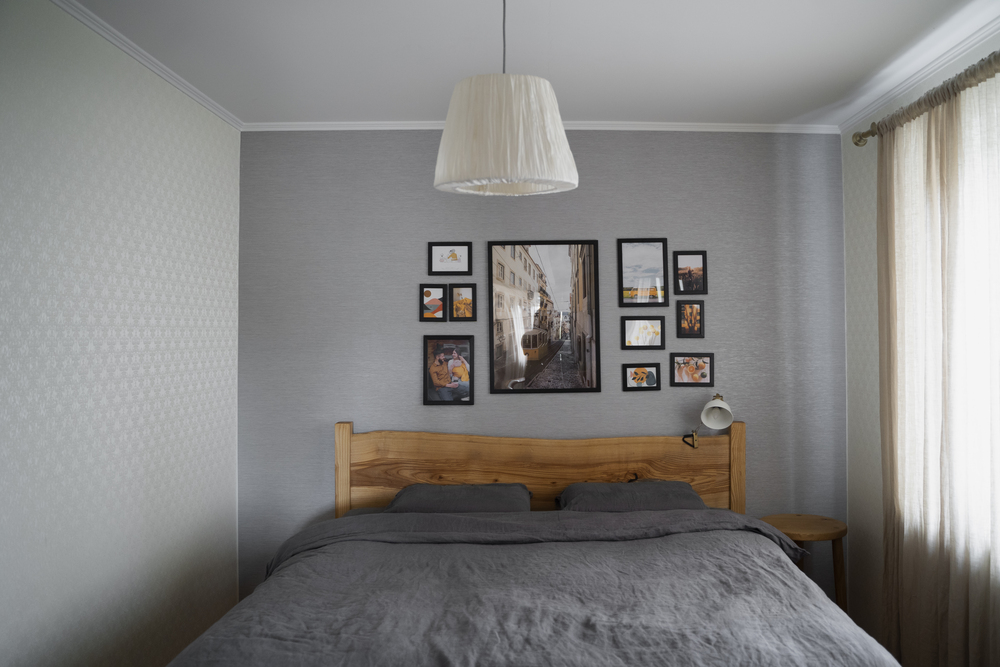 Este dormitorio combina paredes de tono gris neutro con mobiliario de madera y decoraciones minimalistas, aprovechando la luz natural y elementos decorativos sutiles para un ambiente relajante y moderno.