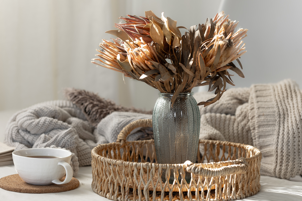 Vista de un rincón acogedor con un jarrón decorativo y una taza de café, rodeado de elementos naturales y texturas cálidas, reflejando las tendencias de decoración de otoño de 2024.